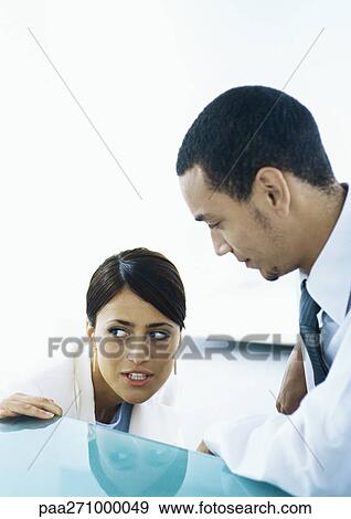 Businesswoman looking out of the corners of her eyes, speaking to businessman View Large Photo Image Stock Photo - Businesswoman looking out of the corners of her eyes, speaking to businessman. Fotosearch