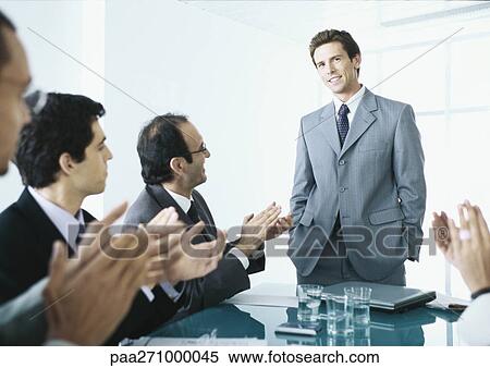 Seated businesspeople applauding businessman standing at end of table View Large Photo Image Stock Photography - Seated businesspeople applauding businessman standing at end of table. Fotosearch