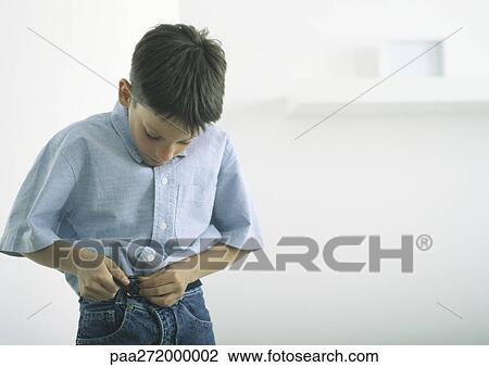 Stock Image - Boy fastening belt. Fotosearch