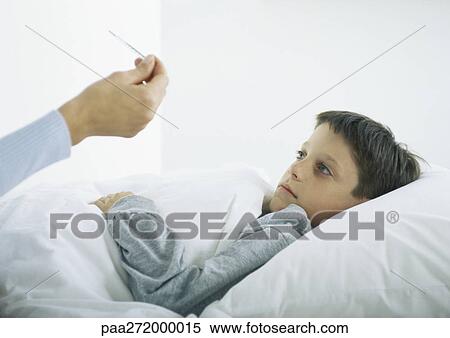 Stock Photography - Boy in bed, woman's hand holding thermometer. Fotosearch