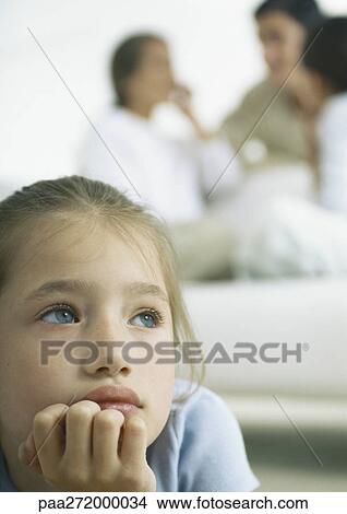Girl holding chin, parents and girl in background View Large Photo Image Picture - Girl holding chin, parents and girl in background. Fotosearch