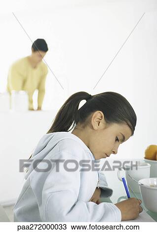 Girl sitting at table writing, man in background View Large Photo Image Stock Image - Girl sitting at table writing, man in background. Fotosearch