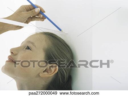 Girl with head against wall being measured by woman View Large Photo Image Stock Photo - Girl with head against wall being measured by woman. Fotosearch