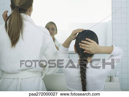 Stock Photo - Woman and girl fixing hair, rear view. Fotosearch