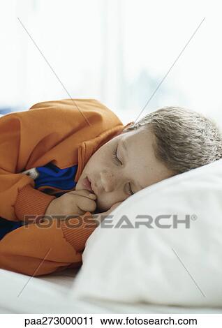 Stock Image - Boy lying down on bed. Fotosearch