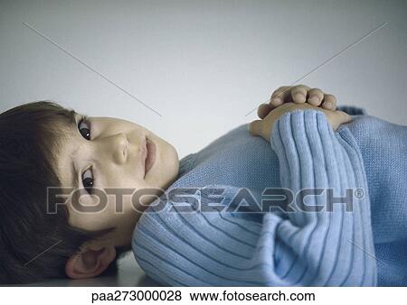 Boy lying down with hands on chest View Large Photo Image Stock Photo - Boy lying down with hands on chest. Fotosearch