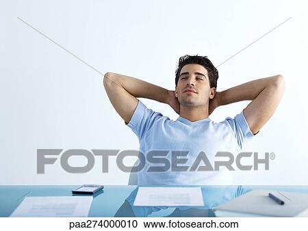 Man sitting at table with hands behind neck and eyes closed View Large Photo Image Stock Image - Man sitting at table with hands behind neck and eyes closed. Fotosearch