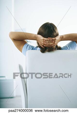 Man sitting on sofa with hands behind head, rear view View Large Photo Image Stock Photograph - Man sitting on sofa with hands behind head, rear view. Fotosearch