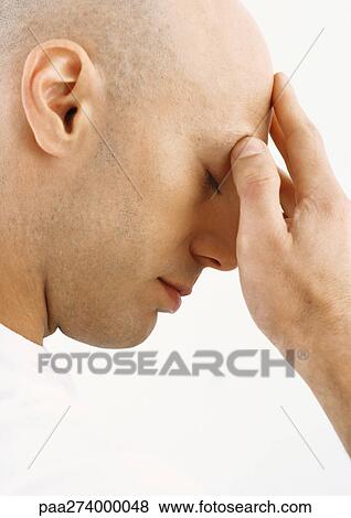 Stock Photo - Man touching forehead, close-up, side view. Fotosearch