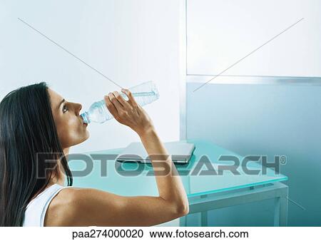 Woman drinking from bottle of water, side view View Large Photo Image Stock Image - Woman drinking from bottle of water, side view. Fotosearch