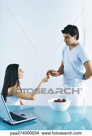 Picture - Woman handing man strawberry. Fotosearch