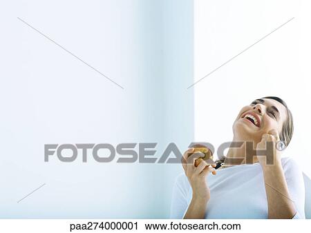Woman holding apple and laughing, on phone View Large Photo Image Stock Image - Woman holding apple and laughing, on phone. Fotosearch