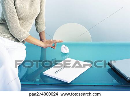 Woman sitting on table, flicking paper ball View Large Photo Image Picture - Woman sitting on table, flicking paper ball. Fotosearch