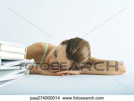 Woman Sleeping With Head On Desk Next To Pile Of Folders Picture