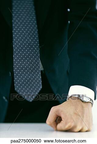 Stock Image - Businessman pressing fist against table, close-up. Fotosearch