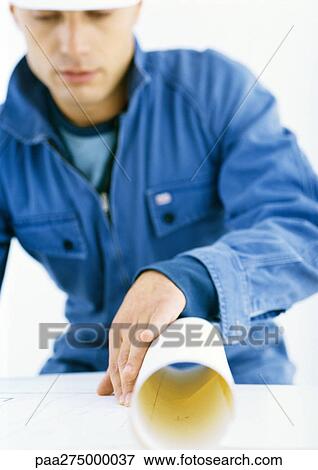 Stock Photo - Man in coveralls looking at blueprints. Fotosearch