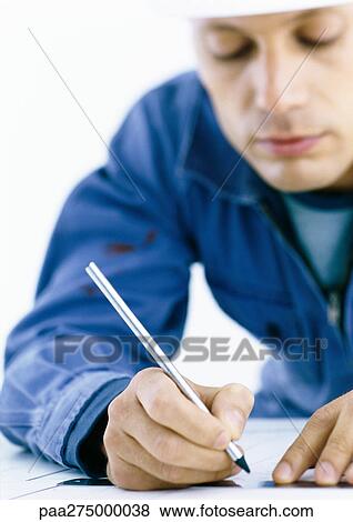 Man in coveralls writing on blueprints View Large Photo Image Stock Photo - Man in coveralls writing on blueprints. Fotosearch