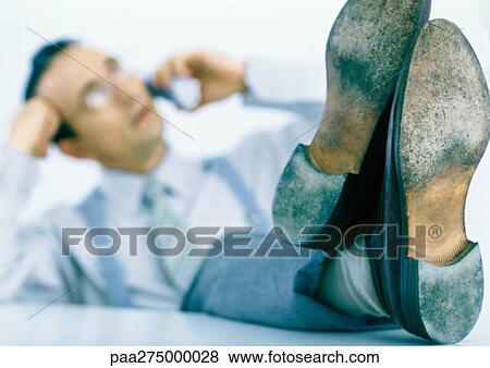 Man talking on phone with feet up on table, focus on feet in foreground View Large Photo Image Stock Photo - Man talking on phone with feet up on table, focus on feet in foreground. Fotosearch
