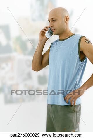 Man with shaved head standing and talking on phone View Large Photo Image Stock Photo - Man with shaved head standing and talking on phone. Fotosearch