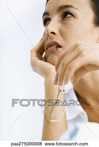 Woman holding head and biting on glasses View Large Photo Image Stock Photo - Woman holding head and biting on glasses. Fotosearch