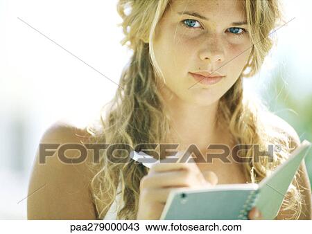 Female student writing in notebook, looking at camera, close-up View Large Photo Image Stock Image - Female student writing in notebook, looking at camera, close-up. Fotosearch