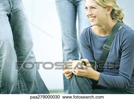 Student sitting and smiling, other students standing in background View Large Photo Image Stock Image - Student sitting and smiling, other students standing in background. Fotosearch