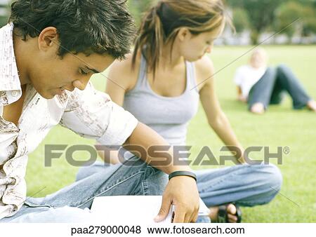 Stock Photo - Students sitting on grass, studying. Fotosearch