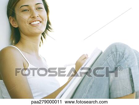 Young woman sitting with knees up, writing View Large Photo Image Stock Image - Young woman sitting with knees up, writing. Fotosearch