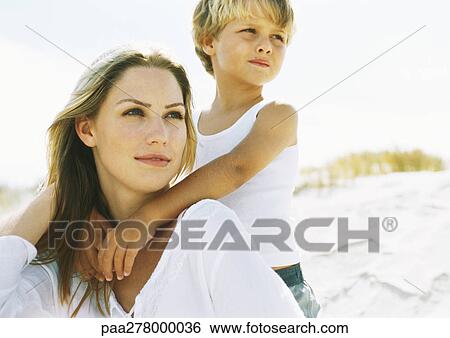 Boy standing behind seated mother on beach, portrait View Large Photo Image Stock Photograph - Boy standing behind seated mother on beach, portrait. Fotosearch