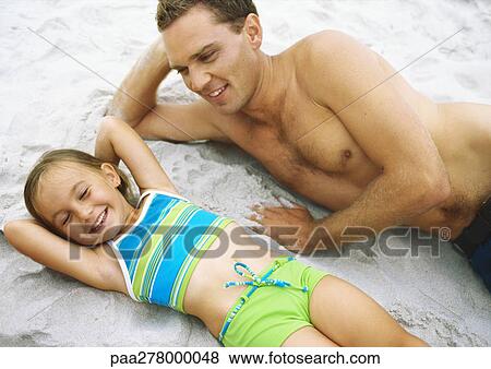 Girl and father lying on beach View Large Photo Image Stock Photo - Girl and father lying on beach. Fotosearch