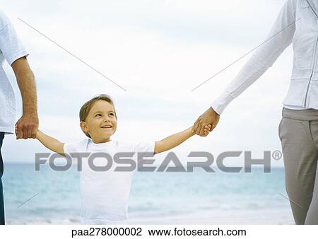 Girl holding parents hands on beach View Large Photo Image Stock Image - Girl holding parents hands on beach. Fotosearch