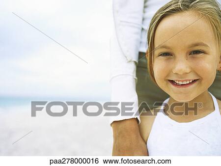 Stock Photograph - Girl leaning against mother on beach. Fotosearch