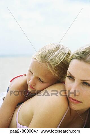 Stock Photo - Girl leaning against mother's back on beach. Fotosearch