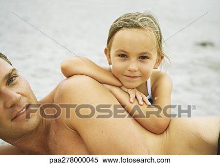 Girl leaning on father's side on beach View Large Photo Image Stock Photography - Girl leaning on father's side on beach. Fotosearch