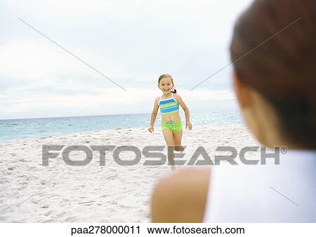 Girl running towards mother on beach View Large Photo Image Stock Image - Girl running towards mother on beach. Fotosearch