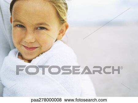 Stock Photo - Girl wrapped in towel on beach, portrait. Fotosearch