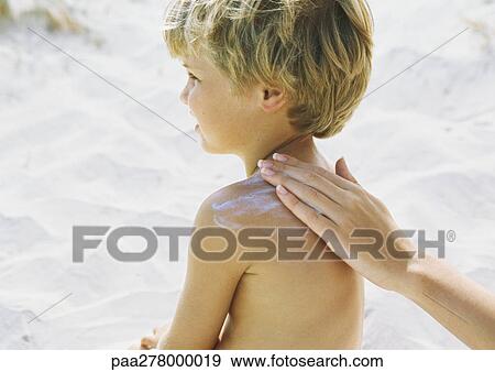 Little boy on beach having sunscreen rubbed into shoulder by mother View Large Photo Image Stock Photo - Little boy on beach having sunscreen rubbed into shoulder by mother. Fotosearch