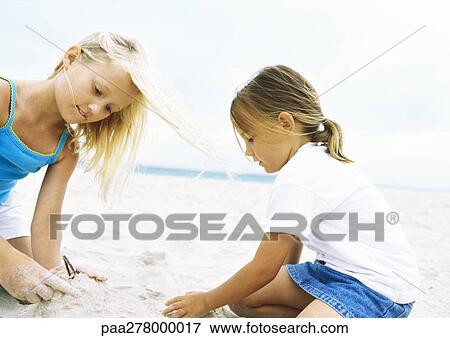 Stock Photo - Two girls playing in sand. Fotosearch