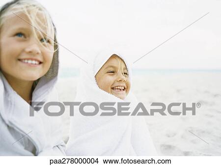 Two girls wrapped up on beach View Large Photo Image Picture - Two girls wrapped up on beach. Fotosearch