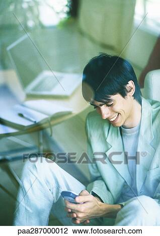 Man smiling and using cell phone View Large Photo Image Stock Image - Man smiling and using cell phone. Fotosearch