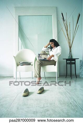 Woman sitting sideways in chair, looking through magazines View Large Photo Image Stock Photo - Woman sitting sideways in chair, looking through magazines. Fotosearch