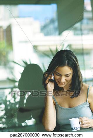 Woman talking on cell phone and holding coffee cup View Large Photo Image Stock Image - Woman talking on cell phone and holding coffee cup. Fotosearch