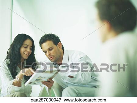 Young adults examining catalog View Large Photo Image Stock Photo - Young adults examining catalog. Fotosearch