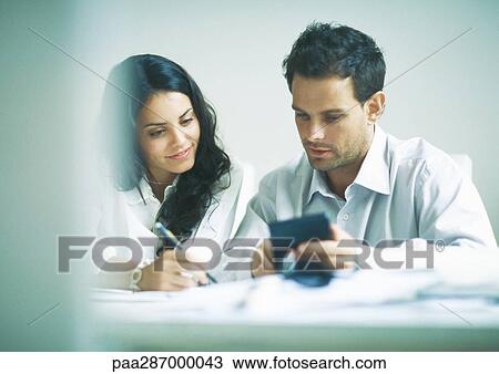 Young adults examining documents and calculating View Large Photo Image Stock Image - Young adults examining documents and calculating. Fotosearch