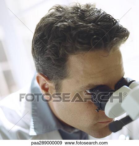 Stock Photo - Doctor looking through microscope. Fotosearch