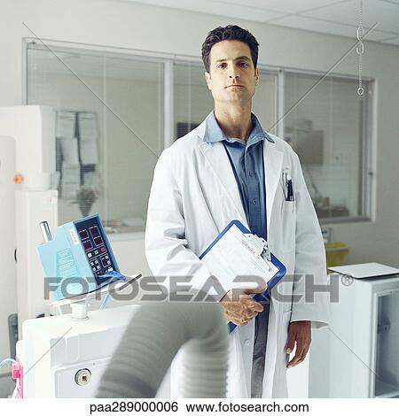 Stock Photograph - Doctor standing in front of medical equipment. Fotosearch