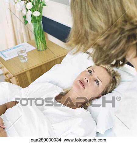 Picture - Hospital patient looking up at woman. Fotosearch