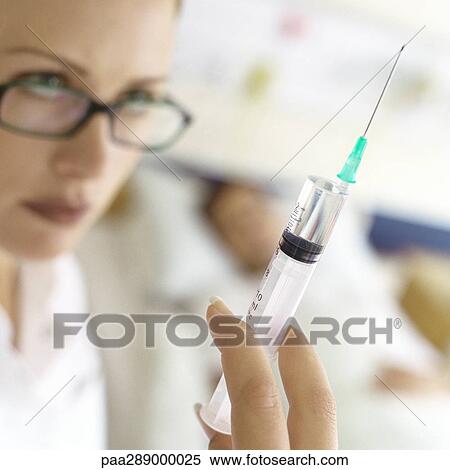 Nurse holding up syringe in front of patient View Large Photo Image Stock Photography - Nurse holding up syringe in front of patient. Fotosearch