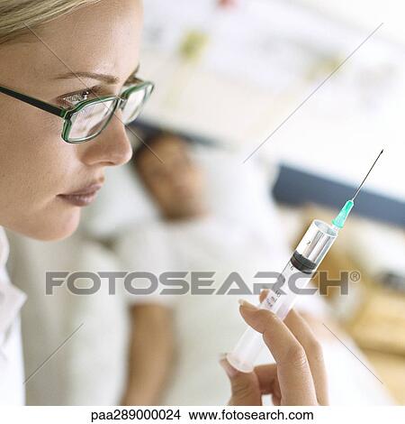 Syringe being held up in front of patient View Large Photo Image Picture - Syringe being held up in front of patient. Fotosearch
