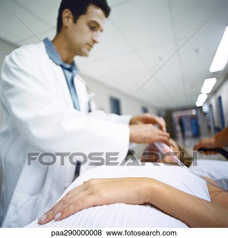 Stock Photo - Doctor adjusting oxygen mask on patient. Fotosearch